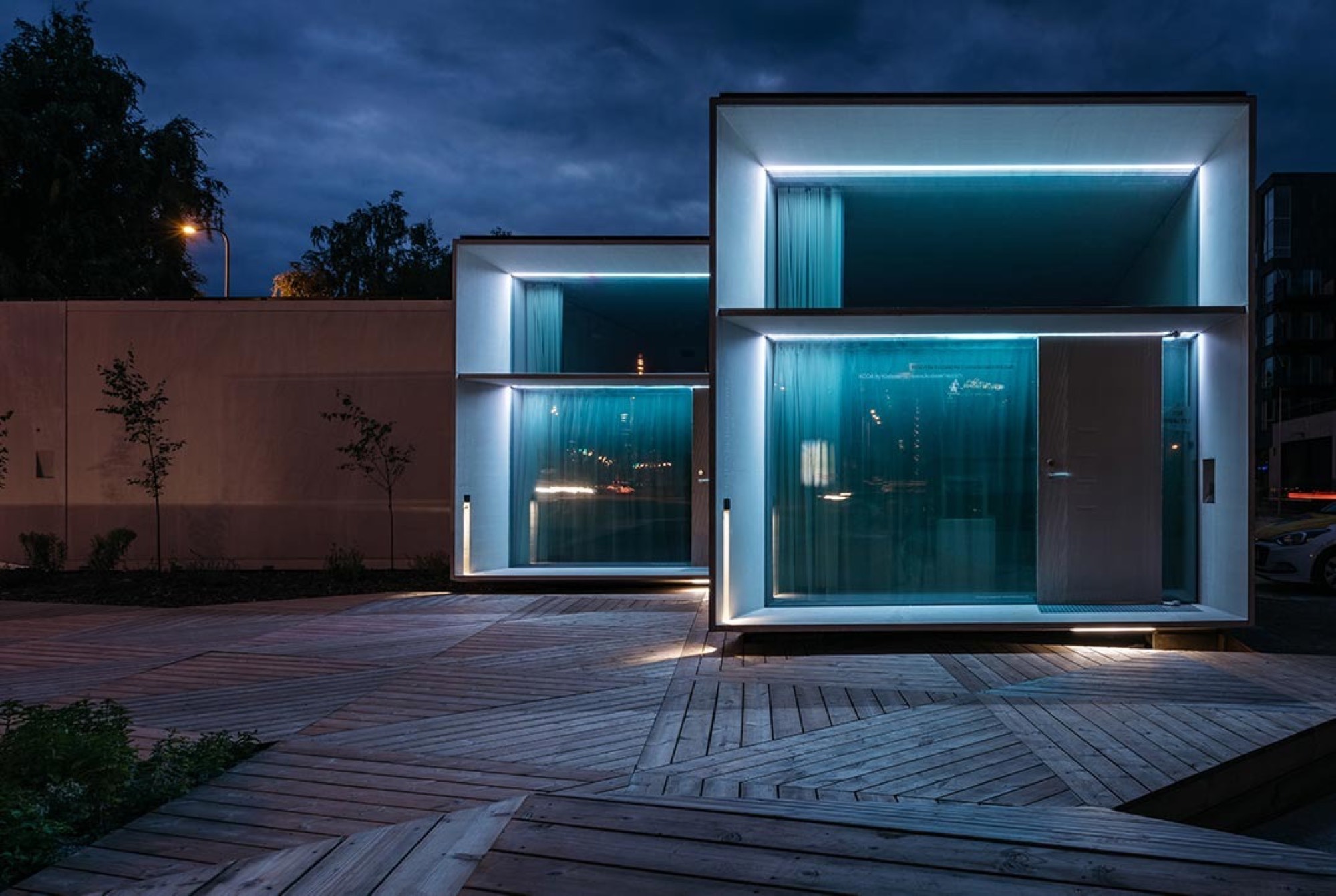 Casa modular LEANOV iluminada ao anoitecer, com deck de madeira
