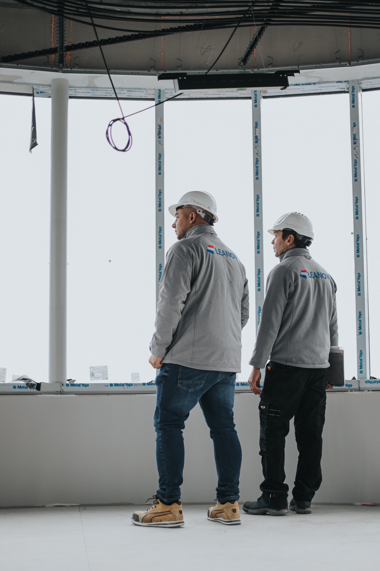 Técnicos LEANOV a observar piso em obra junto a grandes janelas